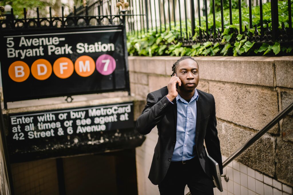 Well dressed African American businessman talking on cellphone while exiting New York subway on summer day