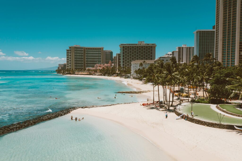 Stunning aerial shot of Waikiki Beach in Honolulu, showcasing clear blue waters and high-rise buildings.