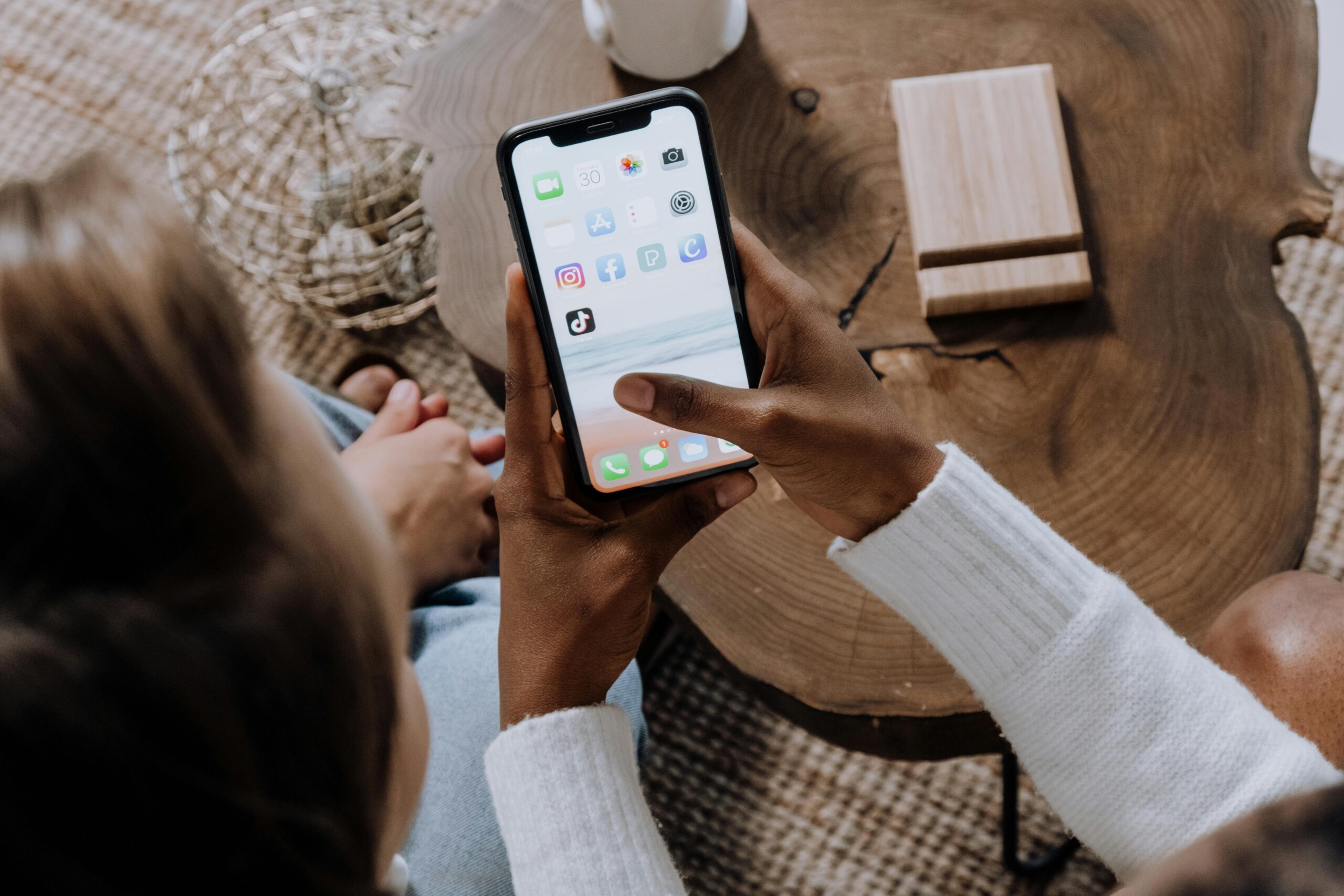 A person using a smartphone with social media apps, sitting at a wooden table. Perfect for tech lifestyle content.