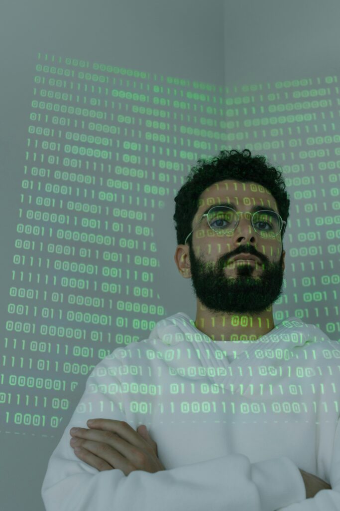 A bearded man in glasses stands with binary code projection, representing cybersecurity and digital intelligence.