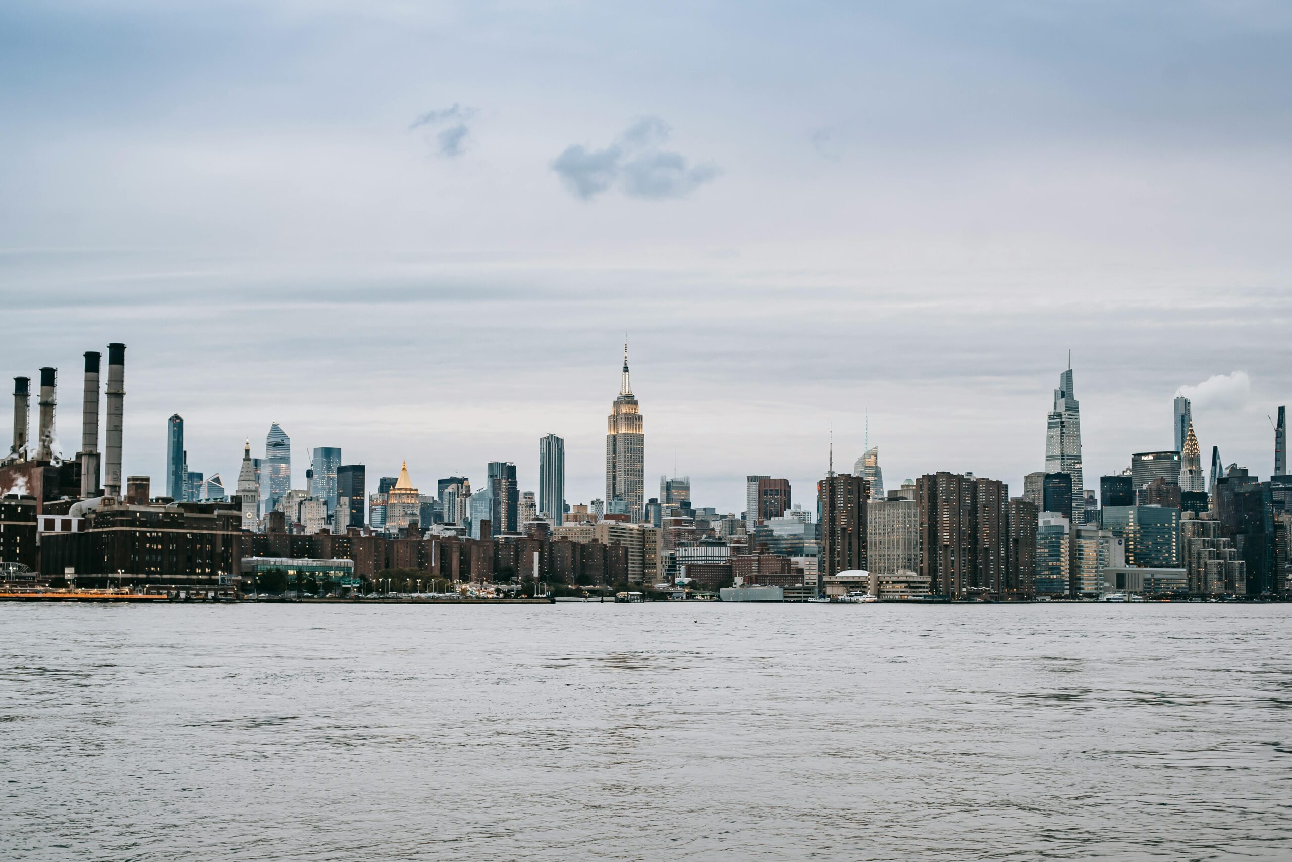 Cityscape of contemporary New York City district with famous skyscrapers situated on East River shore under clear sky