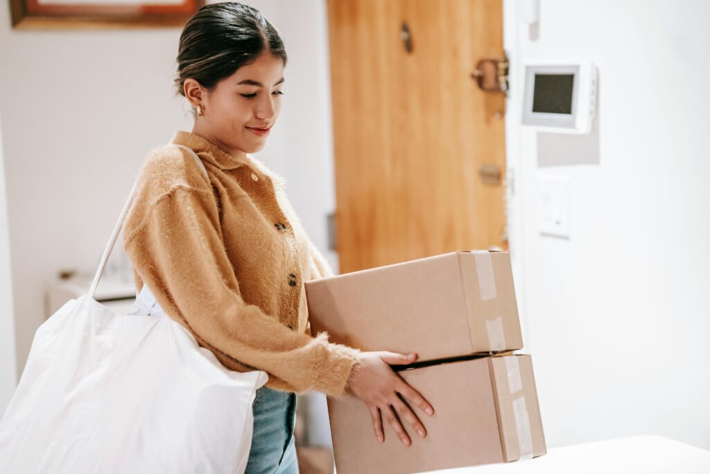 A smiling woman in casual wear delivering packages indoors, showcasing convenience and service.