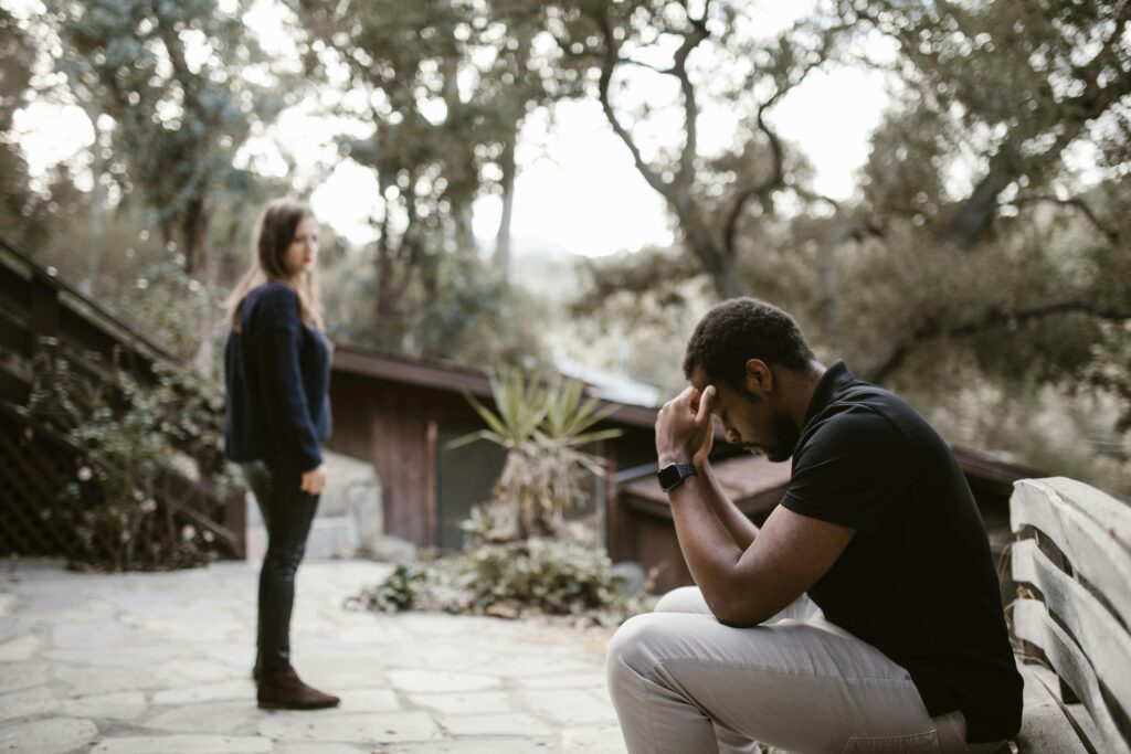 A couple in a tense moment, outdoors on a bench, focusing on emotional distress.