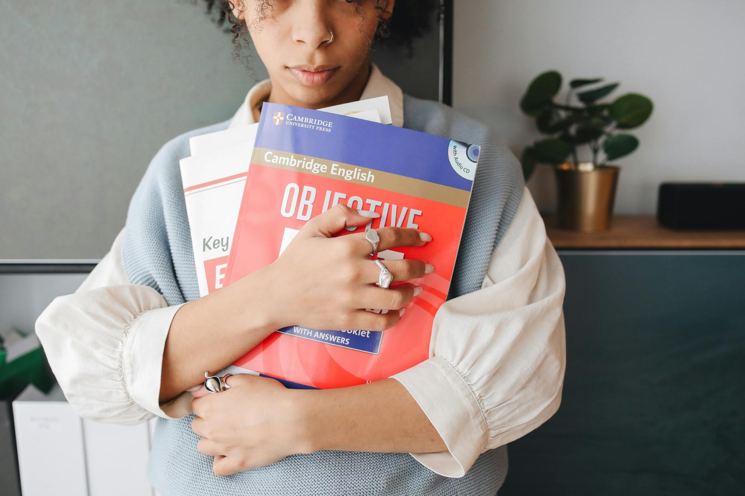 Young woman holding language study books indoors, symbolizing education and learning.