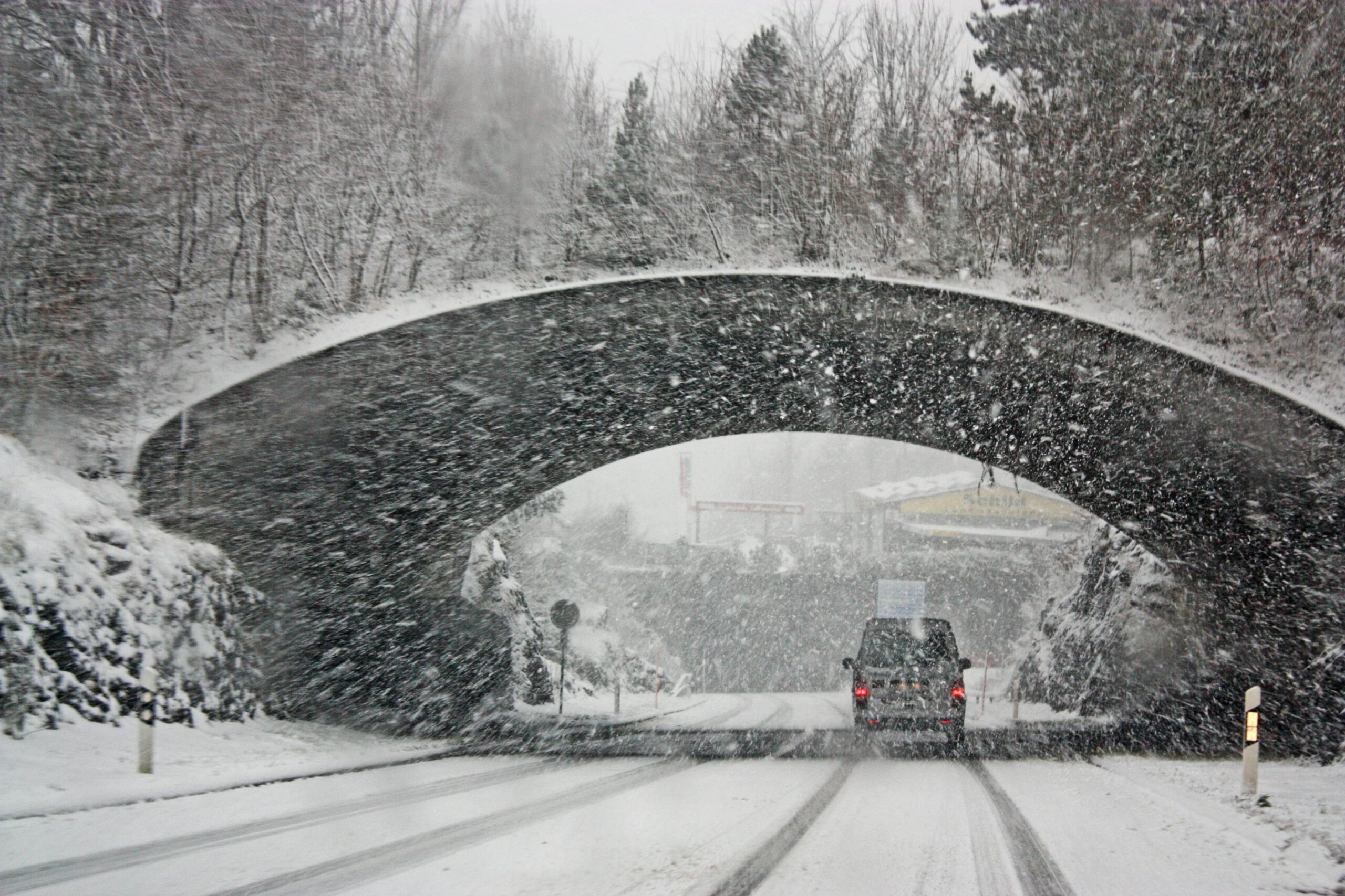 A winter storm covers a Swiss bridge in snow, creating a beautiful yet hazardous landscape.