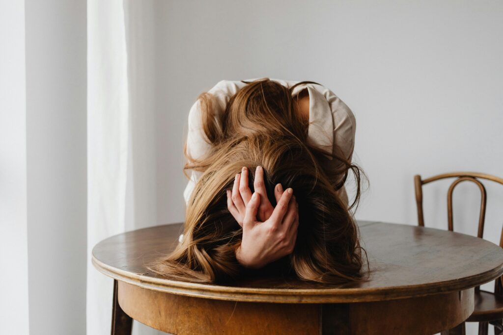 A woman showing despair with her head down on a table, indicating stress.