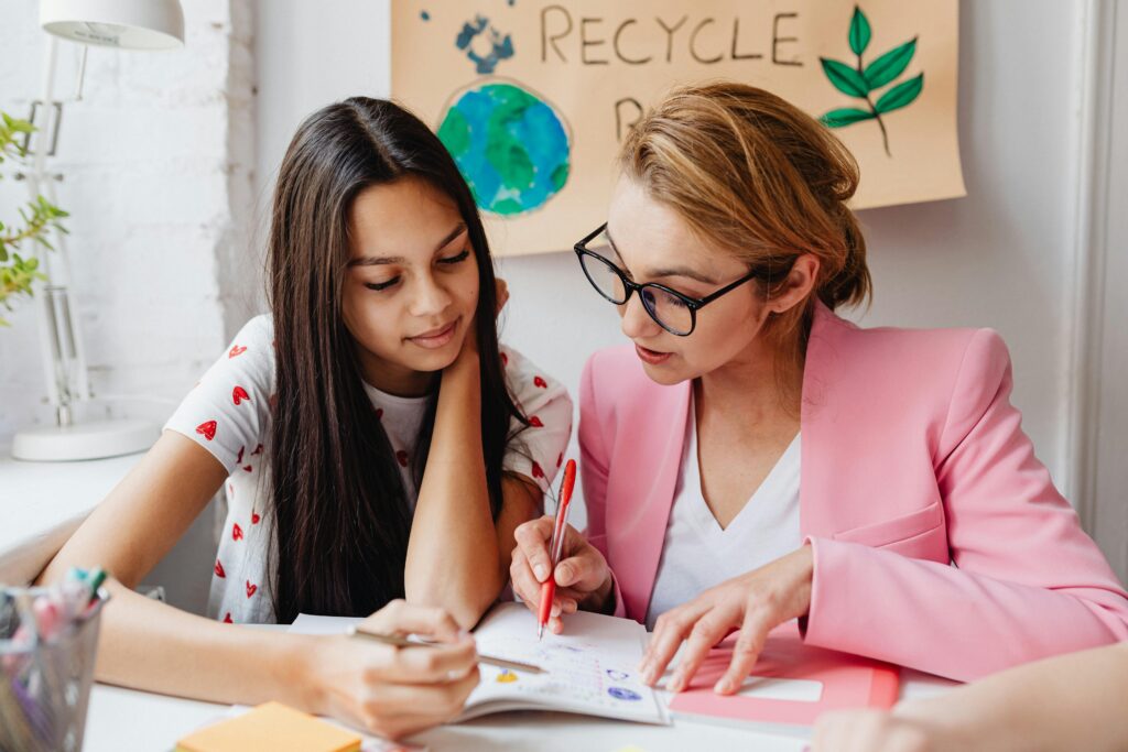 Teacher assists student with homework, promoting educational bonding.