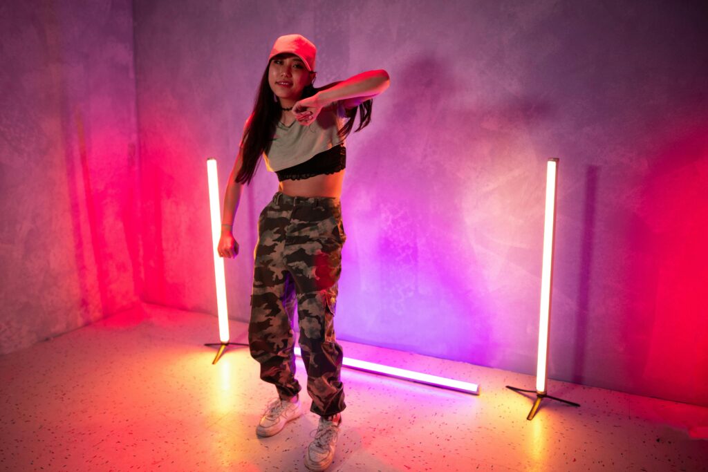 Young woman dancing energetically with vibrant neon lights in a stylish modern setting.