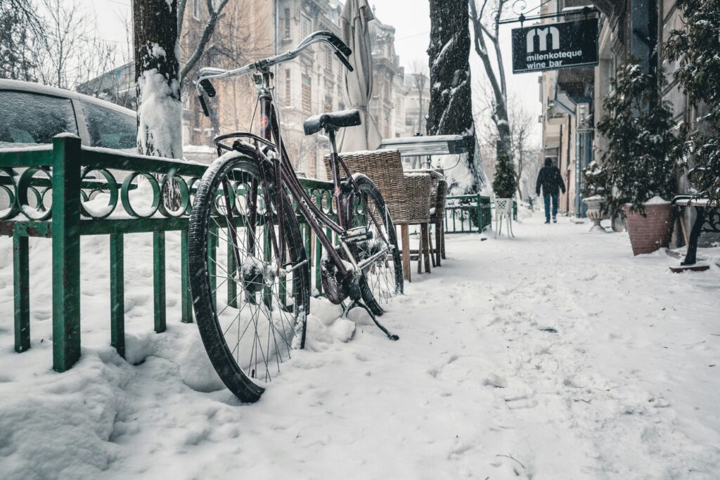 Snow-covered street in Bucharest featuring a bicycle with buildings in the background.