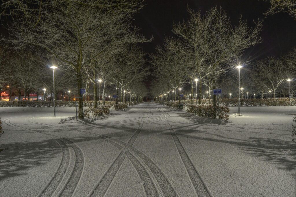 Serene winter night scene in Norrtälje, Sweden with snow and illuminated pathways.