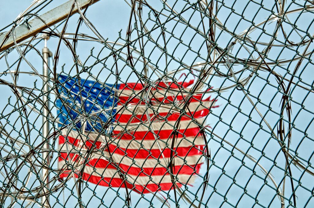 USA flag seen through barbed wire, symbolizing freedom and protection