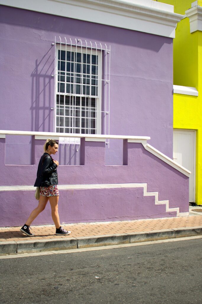 A woman walks by colorful purple and yellow houses in Cape Town's Bo-Kaap.