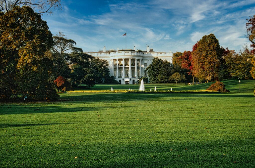 The White House with autumn foliage and a vast green lawn in Washington, D.C.