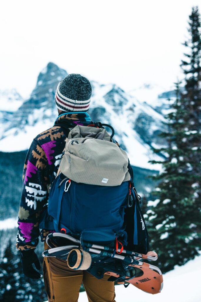 A hiker stands with winter gear, enjoying a scenic mountain view in Banff National Park.