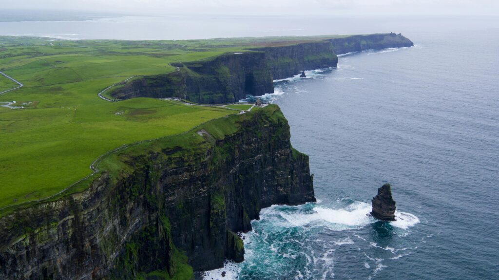 Stunning aerial view of the Cliffs of Moher, County Clare, Ireland with lush green landscapes and ocean waves.