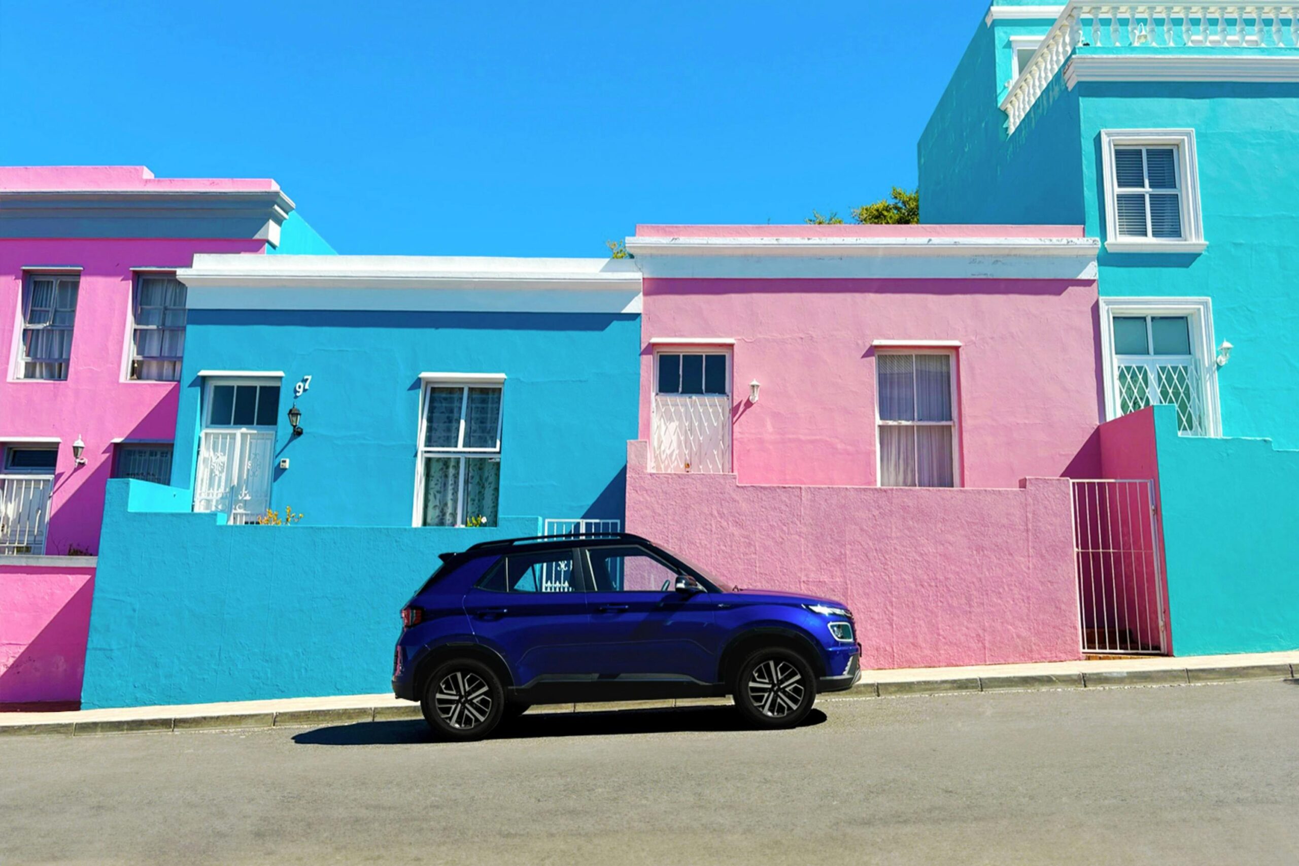 Vibrant city street view with parked SUV and colorful houses in Bo-Kaap, Cape Town.