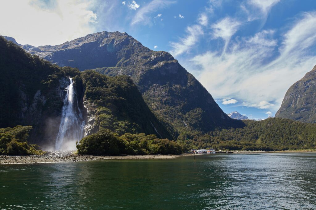 Majestic waterfall at Milford Sound in Fiordland National Park under clear blue skies.