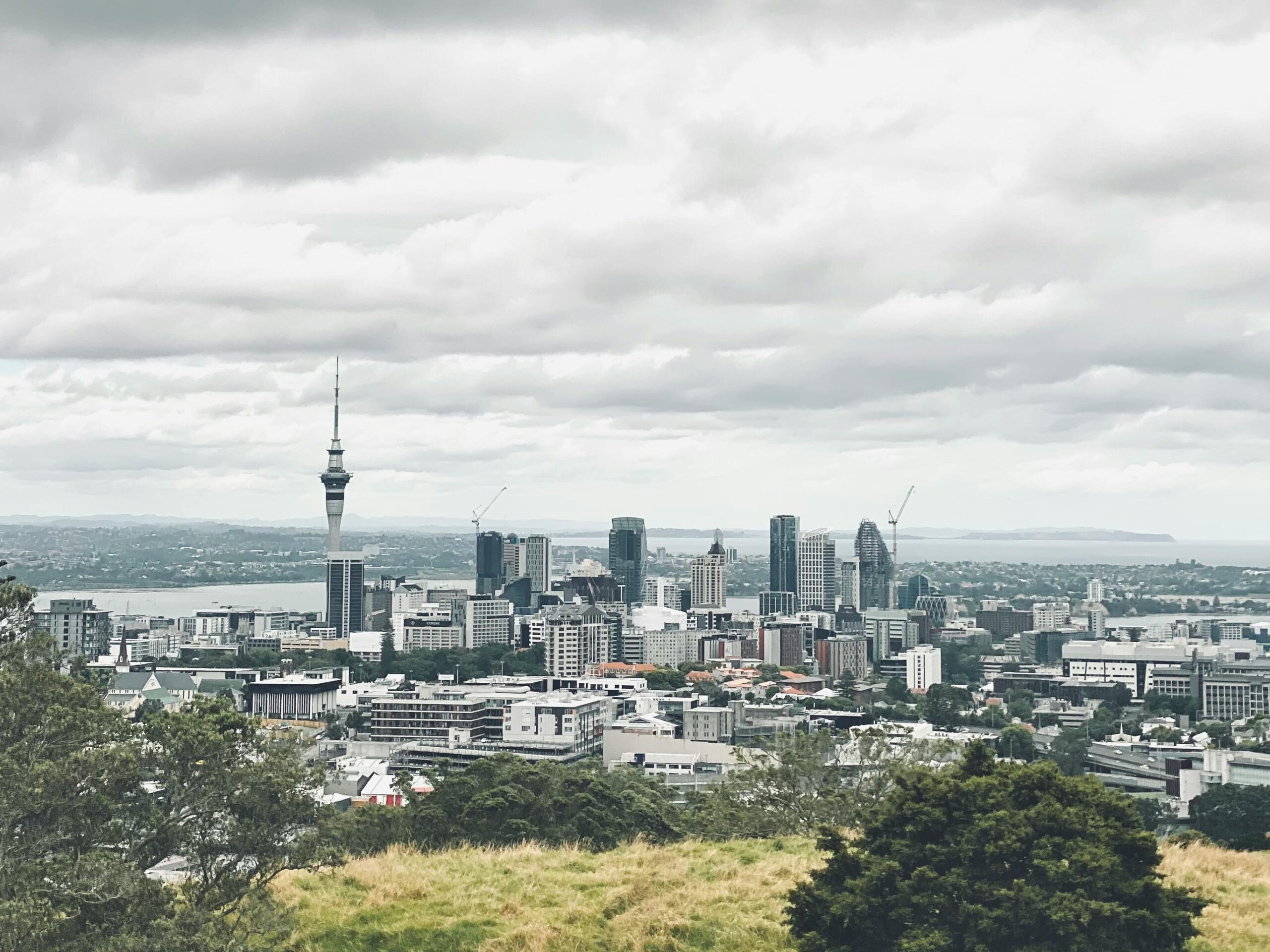 Scenic view of Auckland's skyline featuring the iconic Sky Tower on a cloudy day.