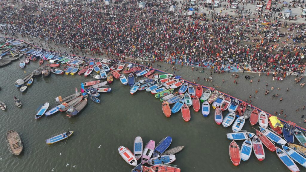 Aerial shot showcasing the bustling crowd and colorful boats at Kumbh Mela in Prayagraj.