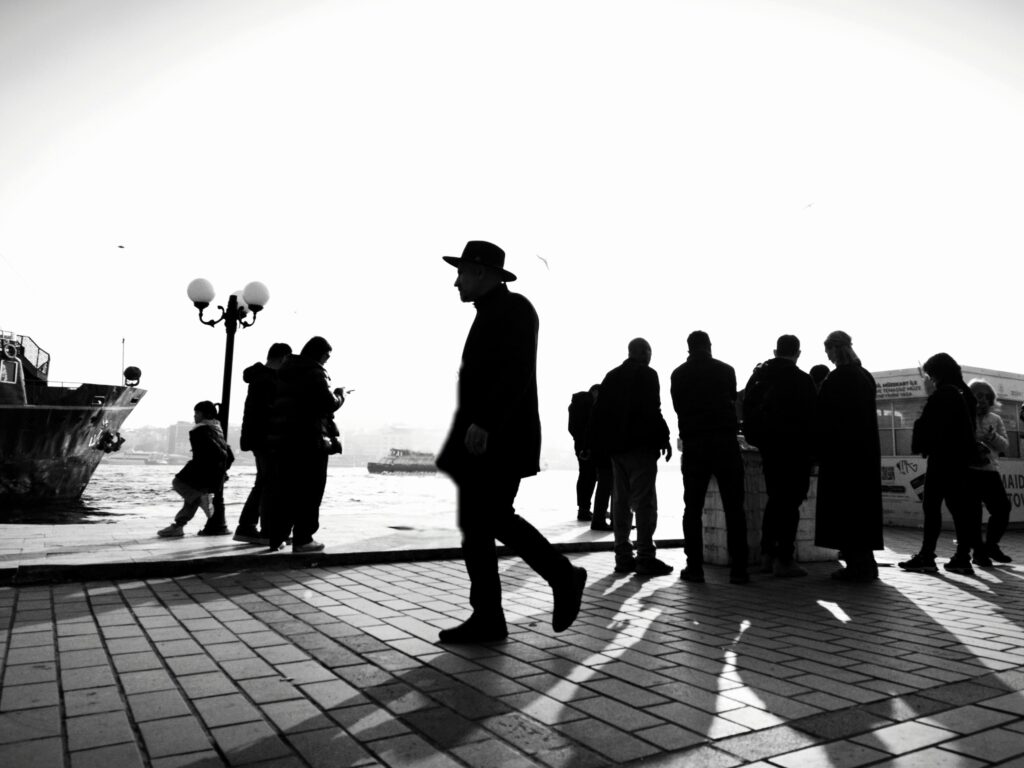 Silhouettes of people by the Bosphorus waterfront in İstanbul, creating a striking black and white scene.