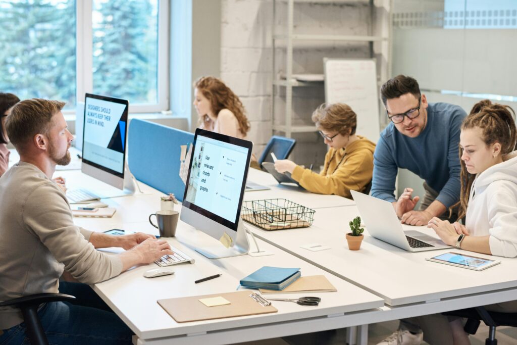 Team collaboration in a modern office setting with computers and diverse employees working together.