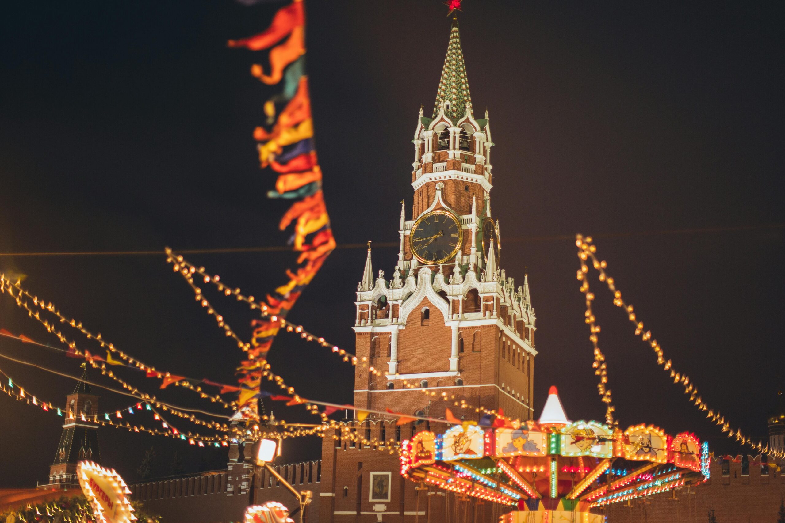 Festive lights and decorations envelop the Kremlin tower at a vibrant night fair.