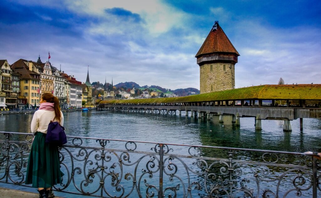 Traveler admires Chapel Bridge and Water Tower in Lucerne, Switzerland.