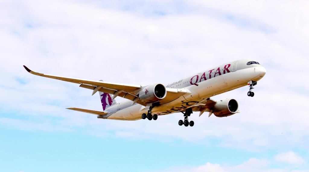 Qatar Airways Airbus A350 aircraft soaring against a blue sky, showcasing modern aviation.