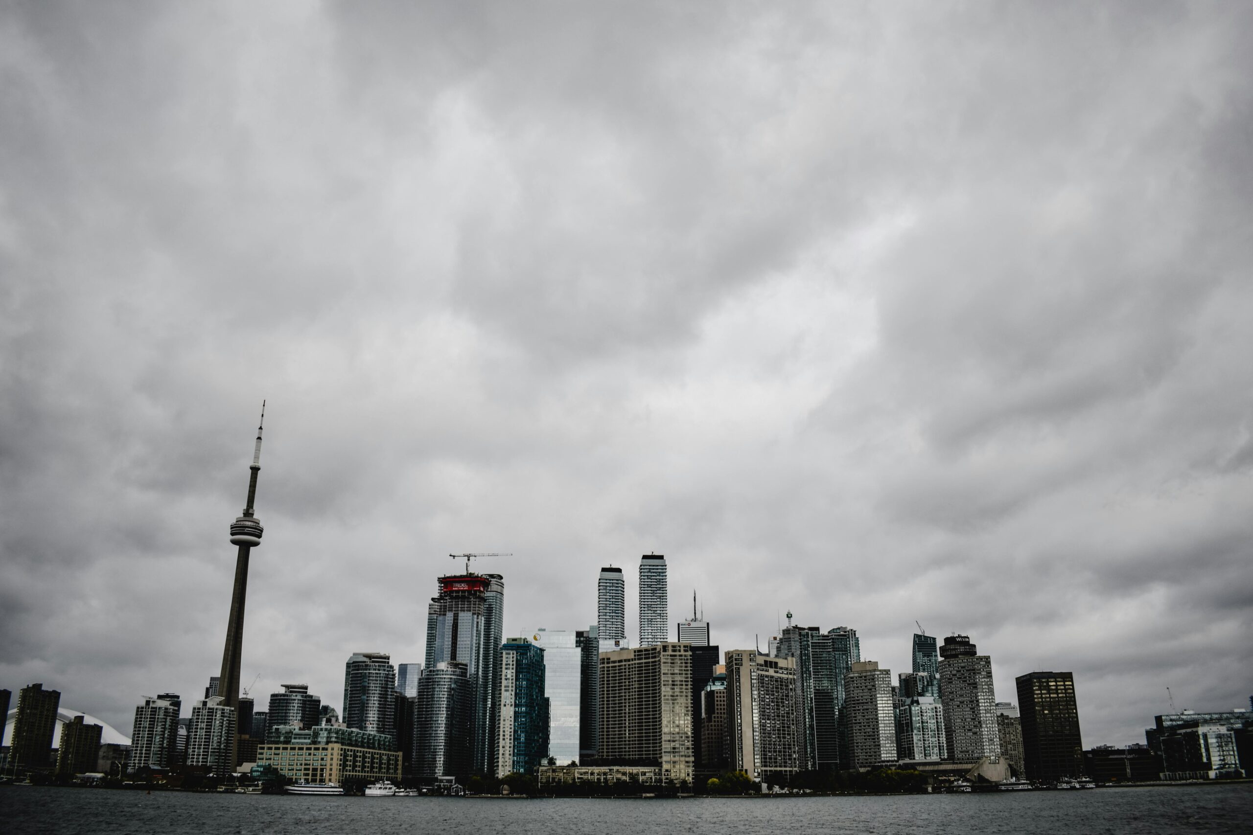 Dramatic view of Toronto's skyline featuring the CN Tower with a moody sky backdrop.