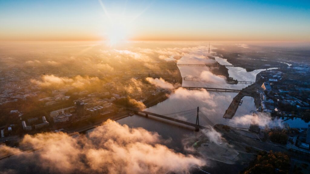 Stunning aerial sunrise view over a city with bridges and a river enveloped in cloud cover.