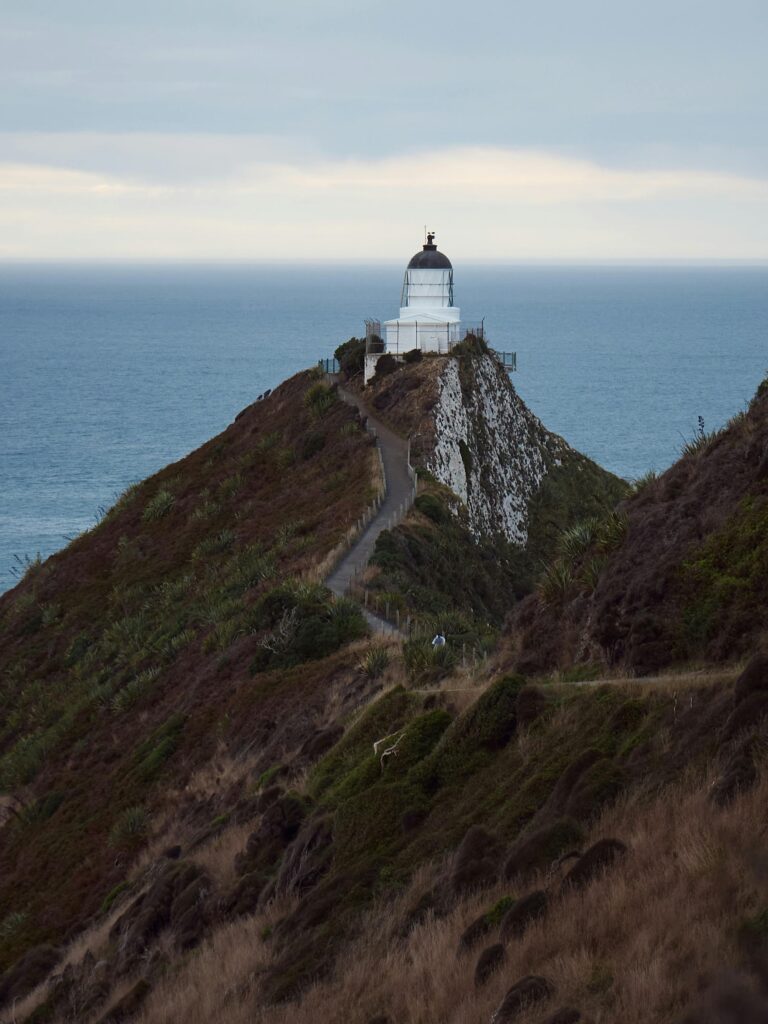 A breathtaking view of Nugget Point Lighthouse with ocean backdrop in New Zealand