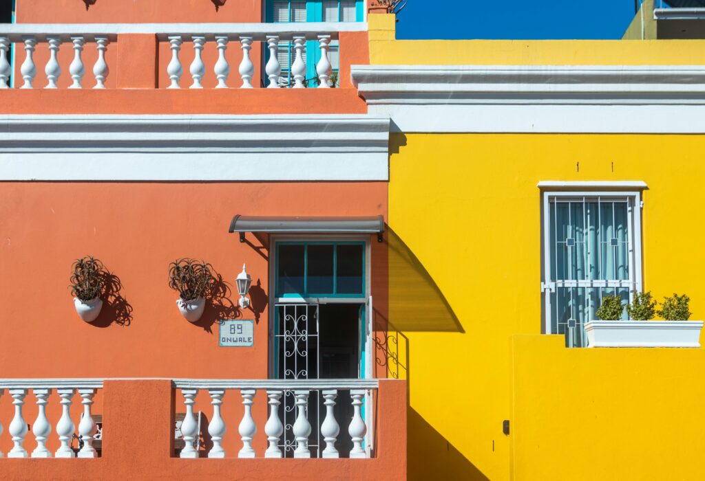 Colorful buildings in the Bo-Kaap neighborhood, Cape Town, showcasing vibrant orange and yellow facades.