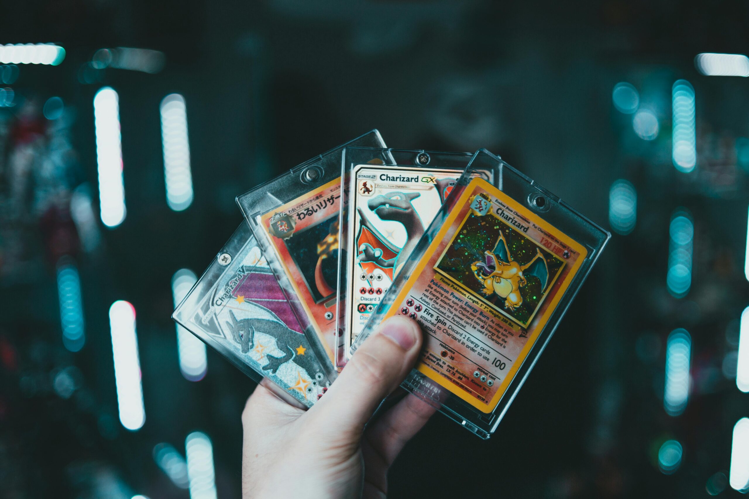 A hand holds collectible Charizard Pokemon cards with a blurred bokeh background. Perfect for trading card enthusiasts.