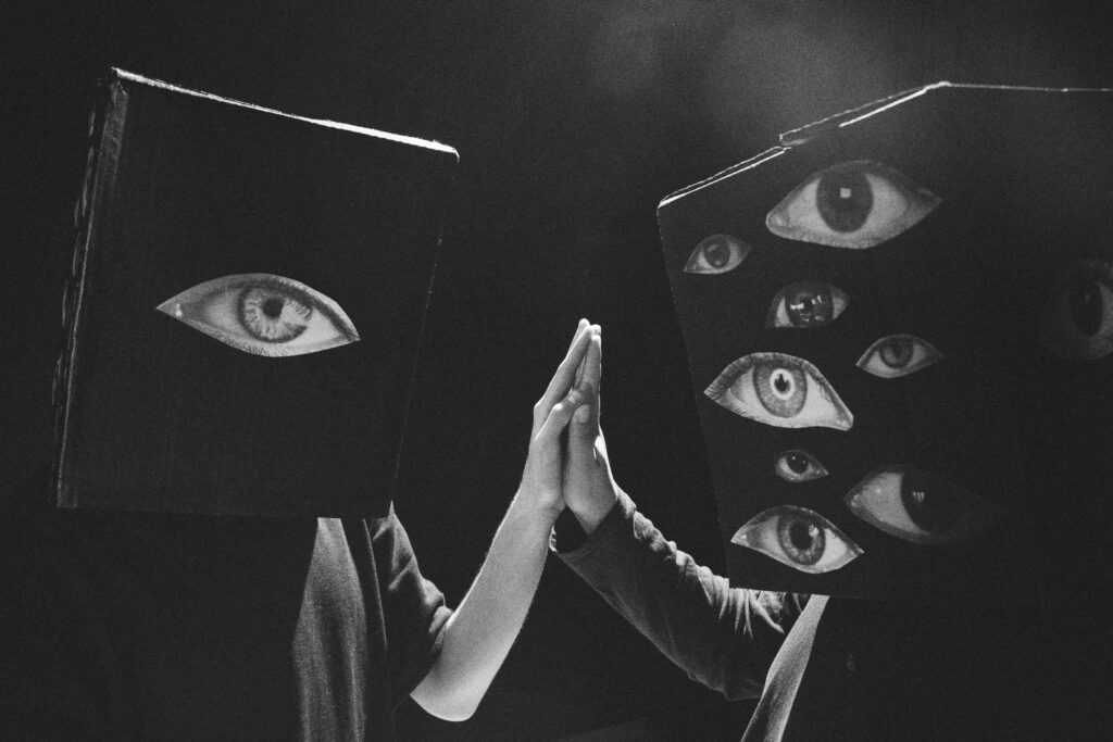 Creative black and white photo of two people with eye-covered cube masks high-fiving.