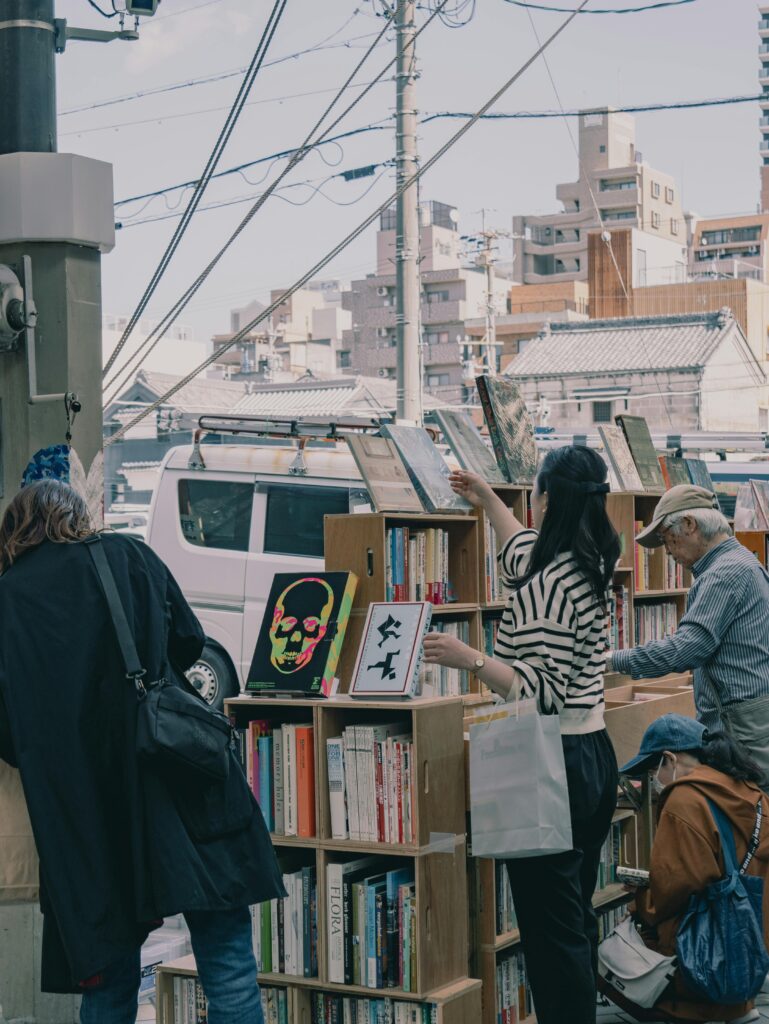 Shoppers browse books at Nagoya's outdoor book market on a sunny day.