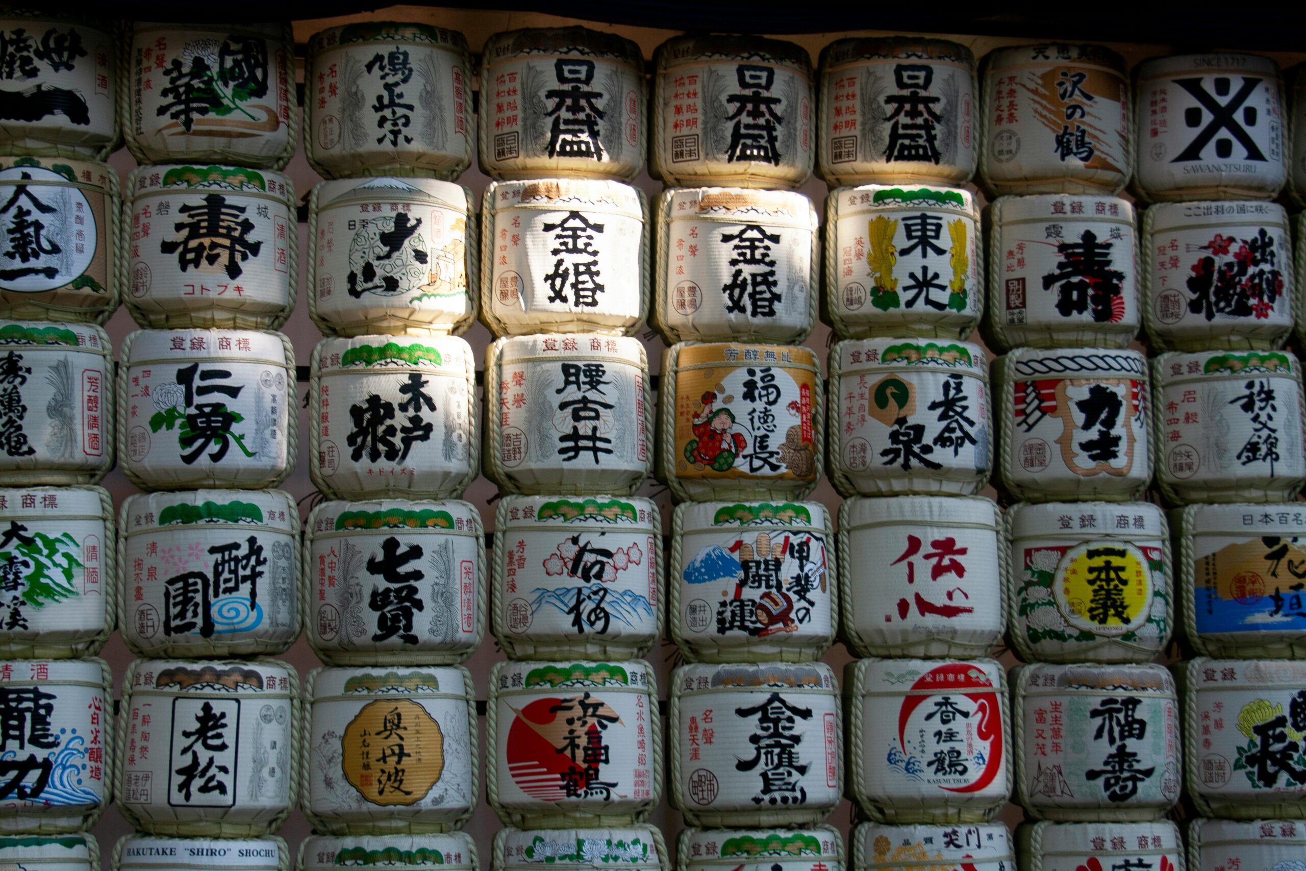 Row of decorative sake barrels in Tokyo, Japan, showcasing intricate calligraphy.