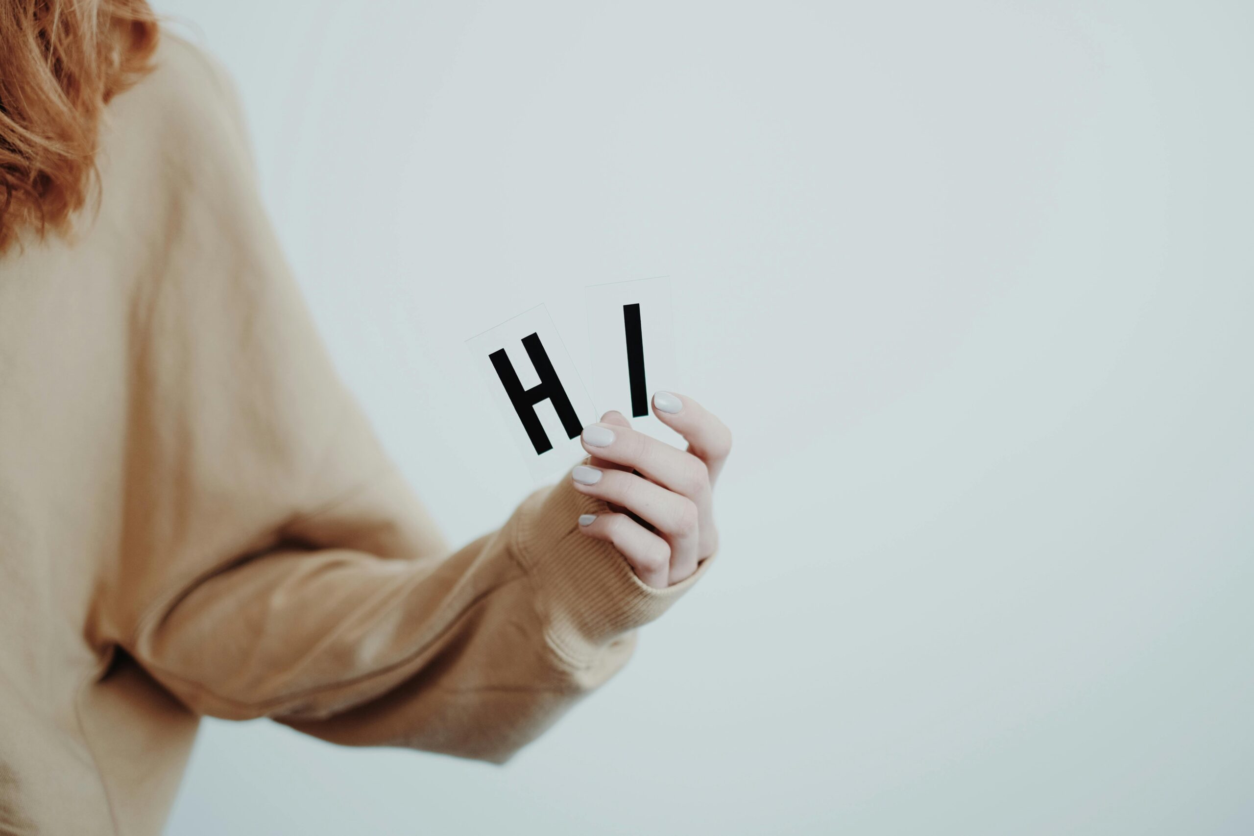 Close-up of a hand holding letters spelling 'Hi' in a minimalist style.