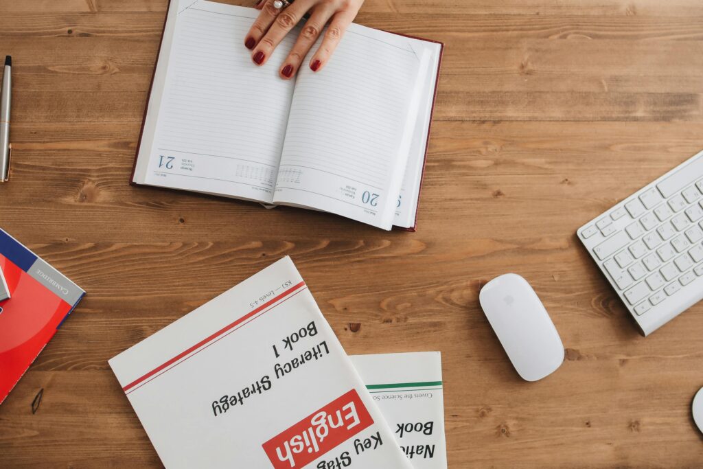 Open planner and English workbooks on a wooden desk, ideal for study-themed visuals.