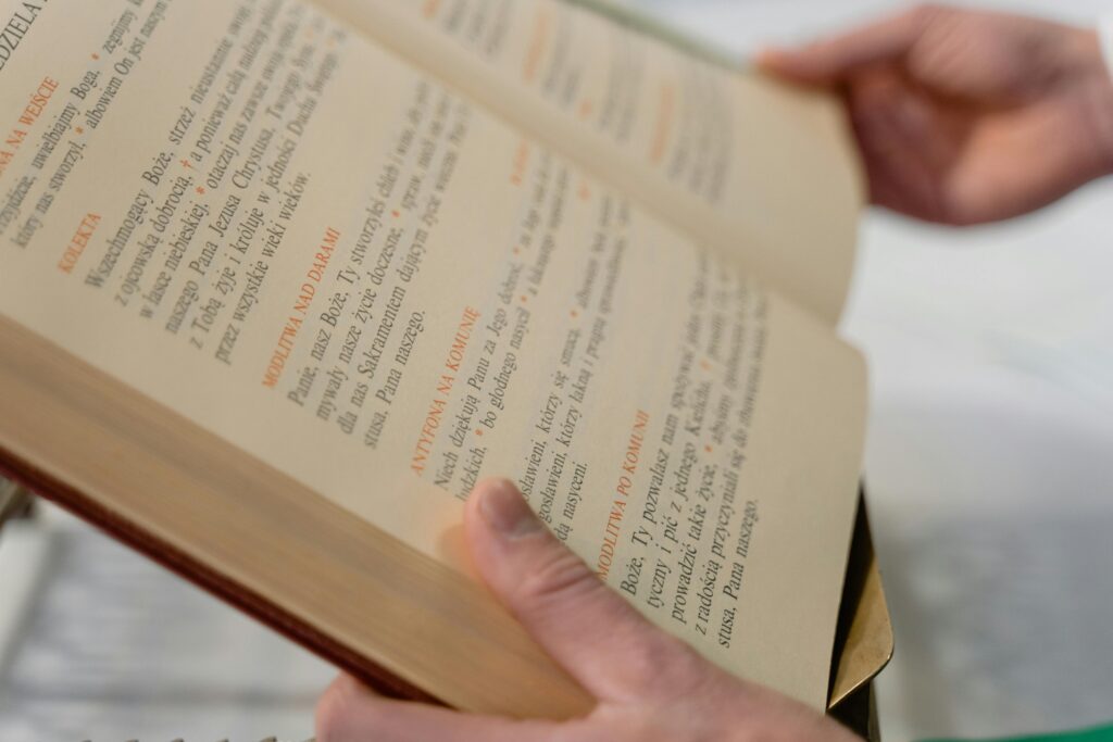 Hands are holding an open religious book with visible text in a church setting.