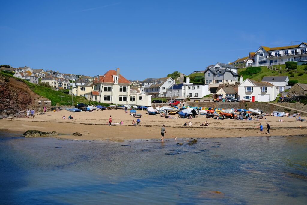 Relaxing summer day at Hope Cove beach with clear skies and vibrant seaside houses in England.