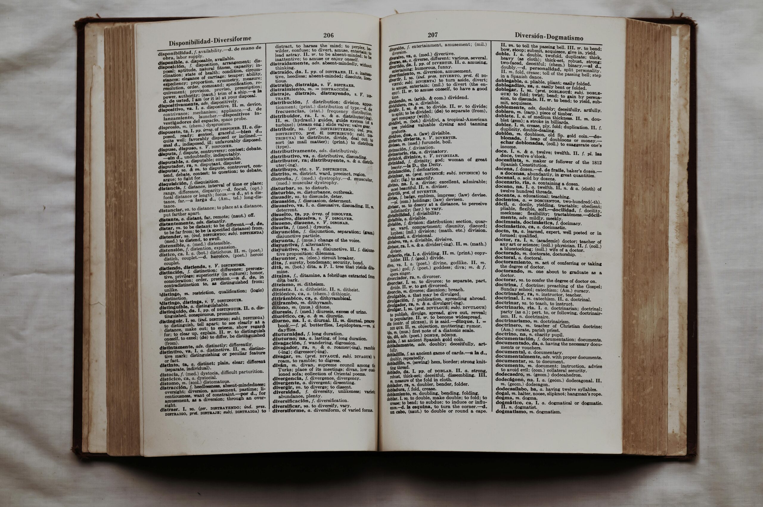 Close-up of an open dictionary showing English and Spanish translations, flat lay view.