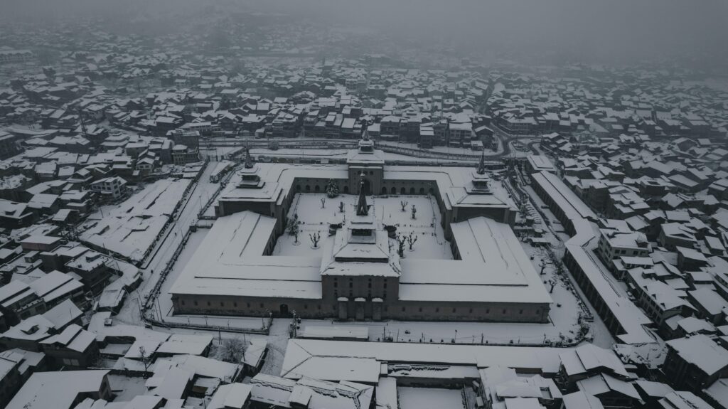 Breathtaking aerial view of a snow-covered mosque in Srinagar, Kashmir during winter.