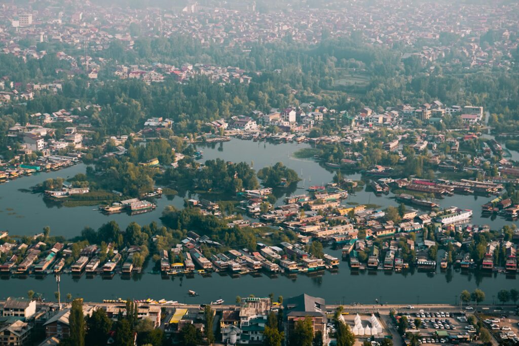 Panoramic aerial view of Dal Lake and Srinagar, showcasing houseboats and lush vegetation.