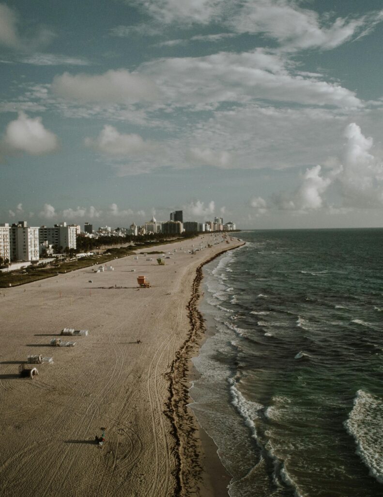 Stunning aerial view of Miami Beach with skyline and ocean waves under a vibrant sky.