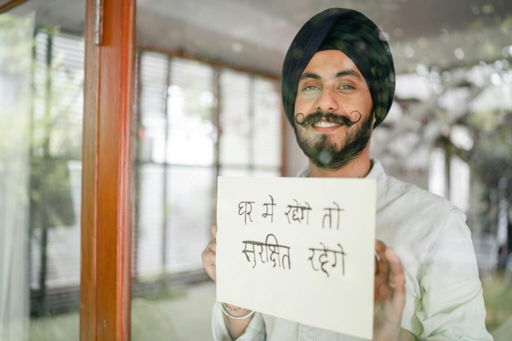 Cheerful man holding a safety message at home through a window.