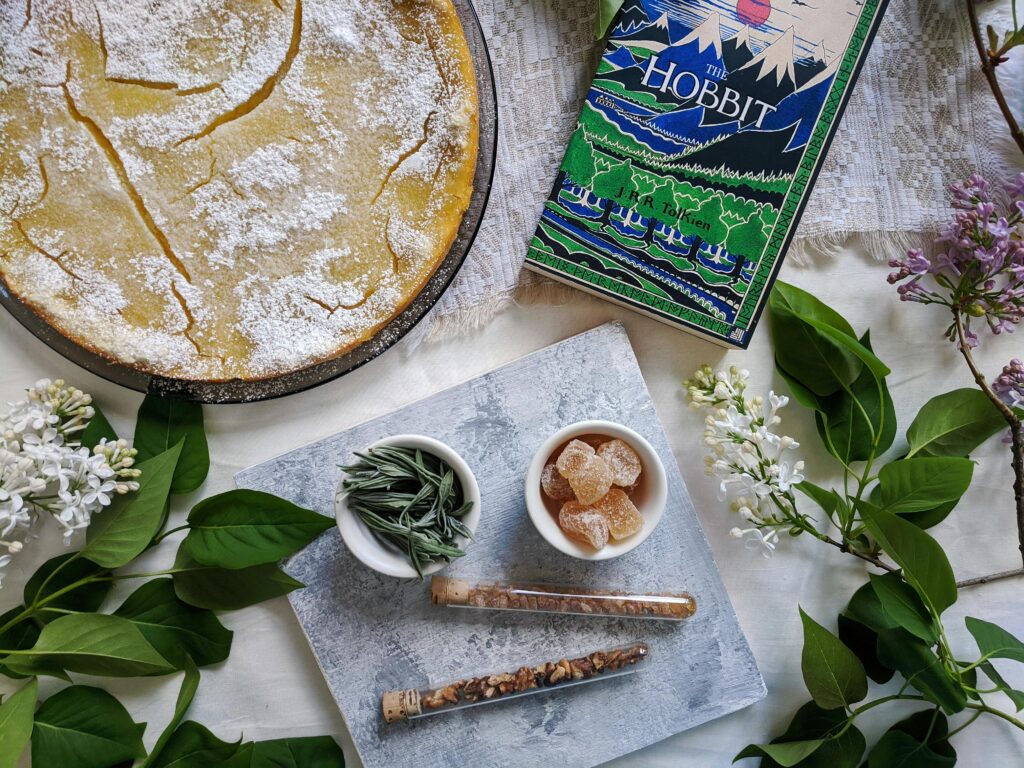 Charming flatlay featuring a lemon tart, herbal elements, and a classic book for a cozy aesthetic.