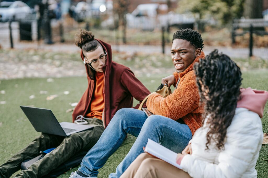 Group of diverse students studying together on a sunny day in the park.