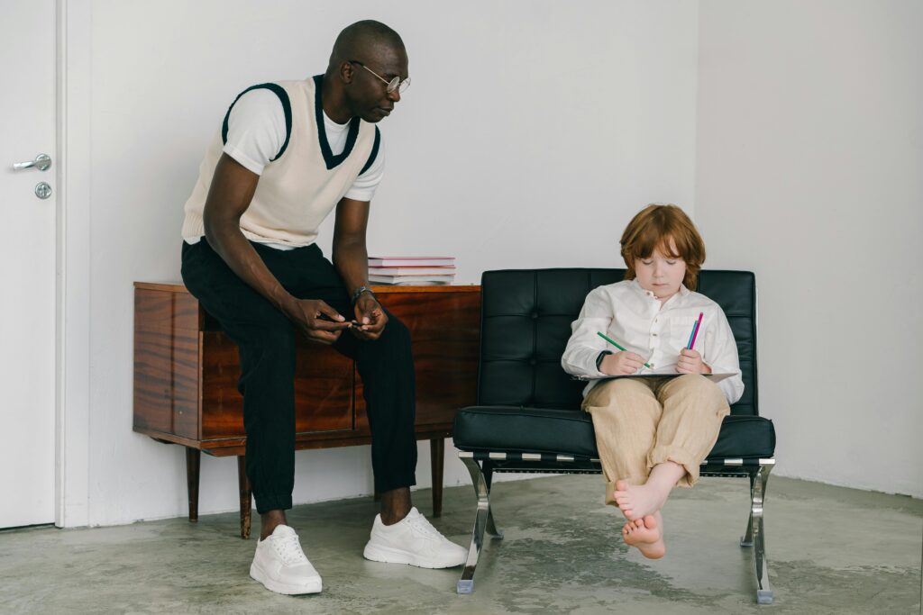A child and adult engage in a therapy session with focus on drawing and communication.