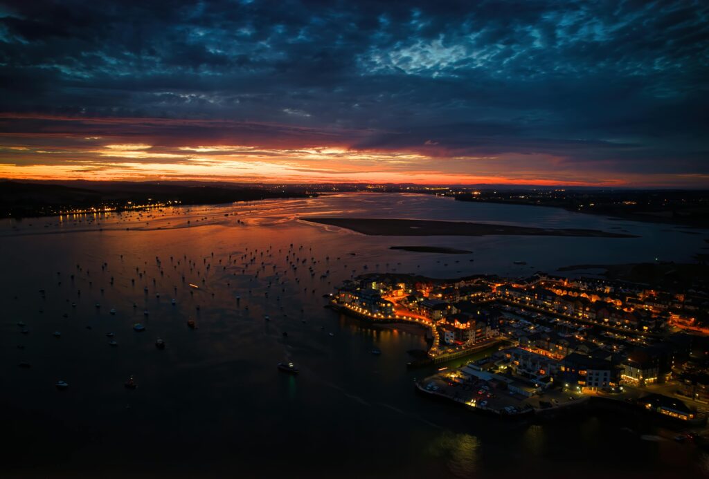 Breathtaking aerial view of Devon coastline, England, showcasing vibrant sunset reflections on water.