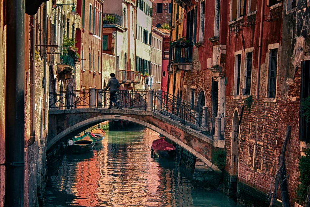 Picturesque Venetian canal with colorful buildings and a bridge in Venice, Italy. Tranquil water and historic charm.